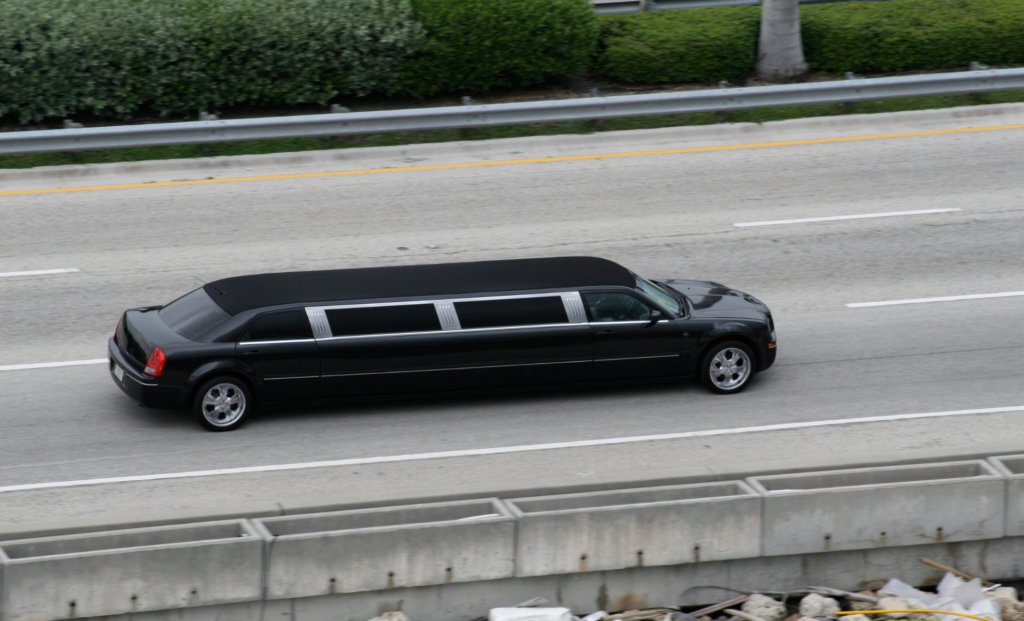 Black stretch limousine driving along a highway