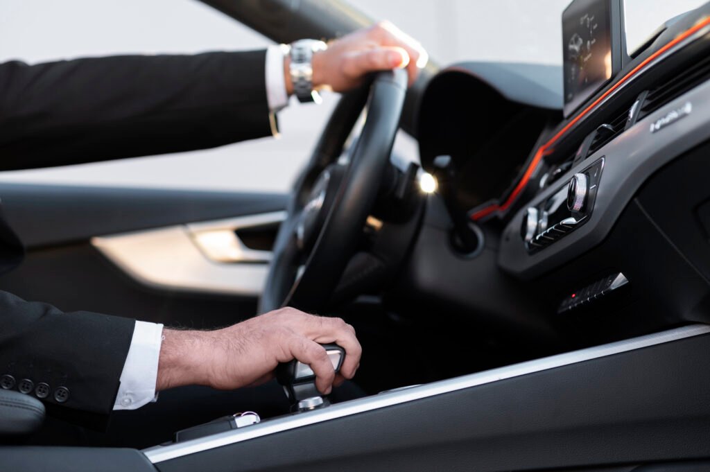 Chauffeur in a suit with hands on the steering wheel and gear selector